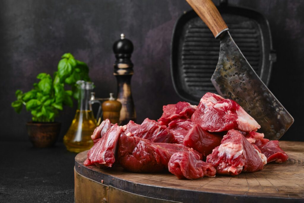 Chopping fresh beef meat on wooden chopping stump