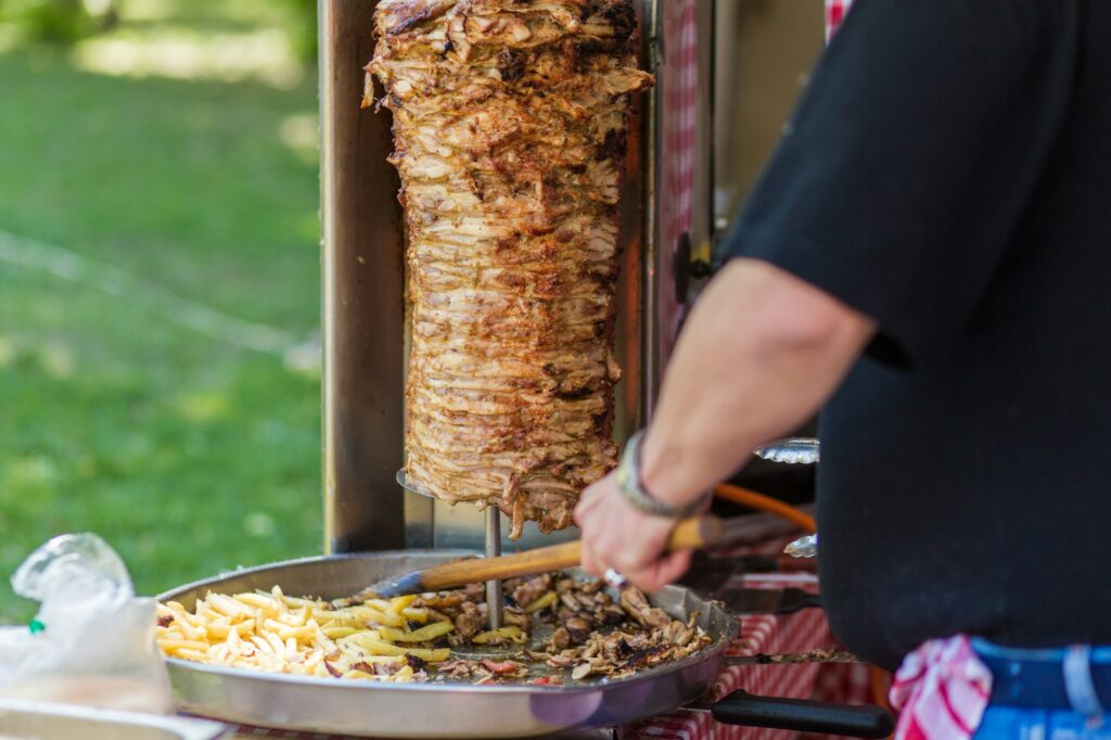 Professional chef makes shawarma. Chef Slicing Doner Meat From Spit At Kebab Shop