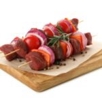 Board with raw shish kebab isolated on white background